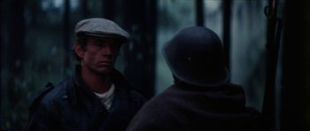 Movie still from “The Keep” (1983), directed by Michael Mann – A man wearing a hat and jacket talking to another man; Close Up shot, Over the shoulder angle