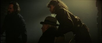 Movie still from “The Keep” (1983), directed by Michael Mann – A man and a woman sitting on top of each other in a dark room; Medium shot, Low angle