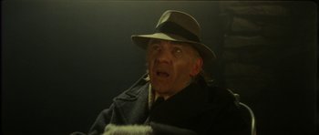 Movie still from “The Keep” (1983), directed by Michael Mann – An old man wearing a hat and a coat; Close Up shot, Over the shoulder angle