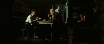 Movie still from “The Keep” (1983), directed by Michael Mann – A group of people sitting at a table eating; Wide shot, Low angle
