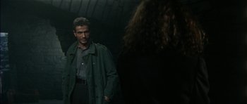 Movie still from “The Keep” (1983), directed by Michael Mann – A man and a woman are standing in a dark room; Medium shot, Over the shoulder angle