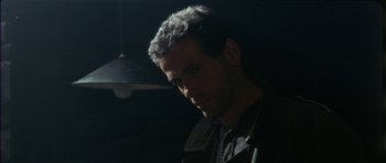 Movie still from “The Keep” (1983), directed by Michael Mann – A person wearing glasses and a jacket; Close Up shot, Over the shoulder angle
