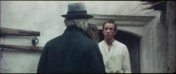 Movie still from “The Keep” (1983), directed by Michael Mann – A man wearing a hat standing next to another man in a hat; Close Up shot, Over the shoulder angle