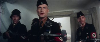 Movie still from “The Keep” (1983), directed by Michael Mann – A man in a military uniform holding a gun; Close Up shot, Low angle