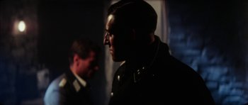 Movie still from “The Keep” (1983), directed by Michael Mann – A man in a black jacket and a man in a black suit; Close Up shot, Over the shoulder angle