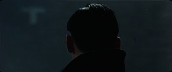 Movie still from “The Keep” (1983), directed by Michael Mann – A man's head is lit up by the light from a window; Close Up shot, Over the shoulder angle