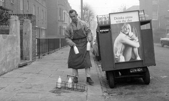 Movie still from “The Knack... and How to Get It” (1965), directed by Richard Lester – A man in an apron is putting milk into a milk truck; Medium shot, Low angle