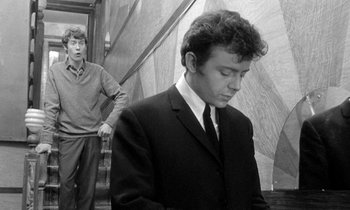 Movie still from “The Knack... and How to Get It” (1965), directed by Richard Lester – A man standing next to another man in a suit; Medium shot, Low angle