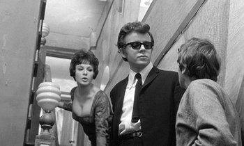 Movie still from “The Knack... and How to Get It” (1965), directed by Richard Lester – A man and a woman standing next to each other in front of another man; Medium shot, Low angle