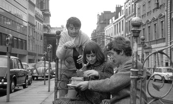 Movie still from “The Knack... and How to Get It” (1965), directed by Richard Lester – A group of people sitting on top of a wooden bench; Medium shot, High angle