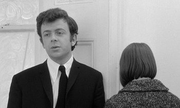 Movie still from “The Knack... and How to Get It” (1965), directed by Richard Lester – A man in a suit and tie standing next to a woman in a suit; Close Up shot, Low angle