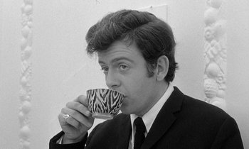 A man in a suit and tie drinking a cup of coffee