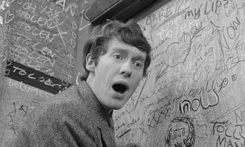 Movie still from “The Knack... and How to Get It” (1965), directed by Richard Lester – A young man is standing in front of a wall covered in graffiti; Close Up shot, Overhead angle