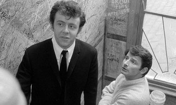 Movie still from “The Knack... and How to Get It” (1965), directed by Richard Lester – A man in a suit and tie standing next to another man in a suit; Medium shot, Low angle