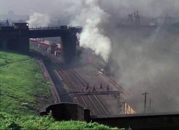 Movie still from “The Ladykillers” (1955), directed by Alexander Mackendrick – A train traveling down train tracks next to a bridge; Extreme Wide shot, High angle