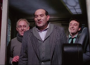 Movie still from “The Ladykillers” (1955), directed by Alexander Mackendrick – A group of men standing next to each other in a room; Medium shot, Low angle