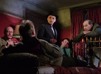 Movie still from “The Ladykillers” (1955), directed by Alexander Mackendrick – A group of men sitting on top of a bed next to each other; Medium shot, Low angle