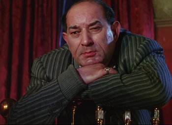 Movie still from “The Ladykillers” (1955), directed by Alexander Mackendrick – An older man sitting in front of a red curtain; Close Up shot, Low angle
