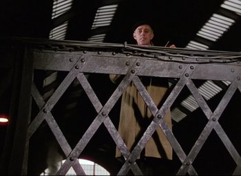 Movie still from “The Ladykillers” (1955), directed by Alexander Mackendrick – A man standing on top of a metal structure; Medium shot, Low angle