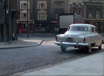 Movie still from “The Ladykillers” (1955), directed by Alexander Mackendrick – An old car parked on the side of the street; Extreme Wide shot, High angle