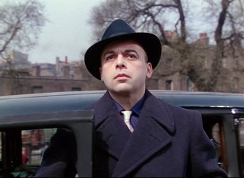 Movie still from “The Ladykillers” (1955), directed by Alexander Mackendrick – A man wearing a hat and a coat; Close Up shot, Low angle
