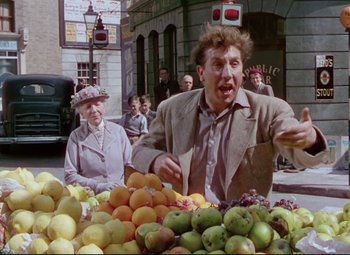 Movie still from “The Ladykillers” (1955), directed by Alexander Mackendrick – An older woman and a young man selling fruit; Medium shot, Over the shoulder angle