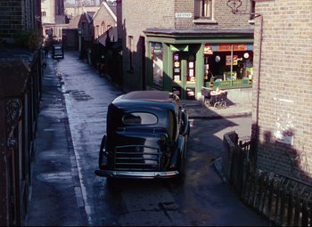 Movie still from “The Ladykillers” (1955), directed by Alexander Mackendrick – An old car parked on the side of the street; Extreme Wide shot, High angle