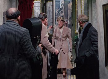 Movie still from “The Ladykillers” (1955), directed by Alexander Mackendrick – An older woman is shaking hands with an older man; Wide shot, Over the shoulder angle