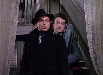 Movie still from “The Ladykillers” (1955), directed by Alexander Mackendrick – Two men standing next to each other in front of a staircase; Medium shot, Low angle