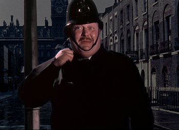 Movie still from “The Ladykillers” (1955), directed by Alexander Mackendrick – A man wearing a helmet and holding a key in his hand; Medium shot, Low angle