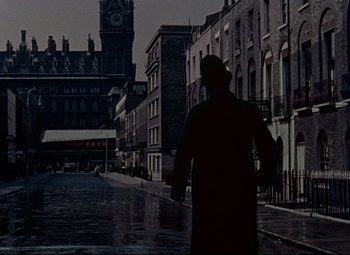 Movie still from “The Ladykillers” (1955), directed by Alexander Mackendrick – A man standing on the side of a street; Wide shot, Low angle
