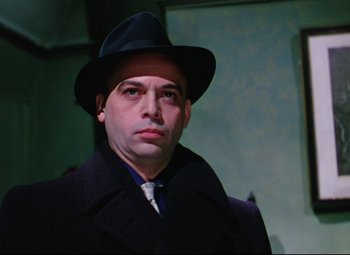 Movie still from “The Ladykillers” (1955), directed by Alexander Mackendrick – A man wearing a hat and a coat; Close Up shot, Low angle