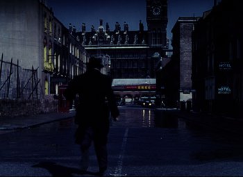 Movie still from “The Ladykillers” (1955), directed by Alexander Mackendrick – A man walking down the street in the dark; Wide shot, Over the shoulder angle