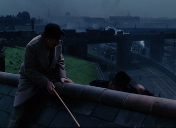 Movie still from “The Ladykillers” (1955), directed by Alexander Mackendrick – A man on the roof of a building looking over a bridge; Wide shot, High angle
