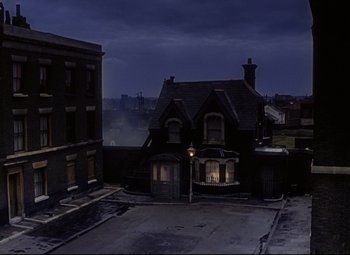 Movie still from “The Ladykillers” (1955), directed by Alexander Mackendrick – An old building with a street light in front of it at night; Extreme Wide shot, High angle
