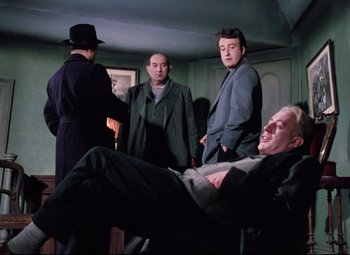 Movie still from “The Ladykillers” (1955), directed by Alexander Mackendrick – A group of men standing next to each other in a room; Medium shot, Low angle