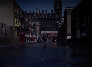 Movie still from “The Ladykillers” (1955), directed by Alexander Mackendrick – A person walking down a street at night; Extreme Wide shot, High angle
