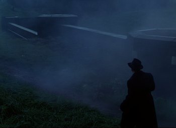 Movie still from “The Ladykillers” (1955), directed by Alexander Mackendrick – A man standing in a field with fog coming from the ground; Extreme Wide shot, High angle