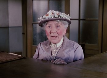 Movie still from “The Ladykillers” (1955), directed by Alexander Mackendrick – An older woman wearing a hat sitting at a table; Close Up shot, High angle
