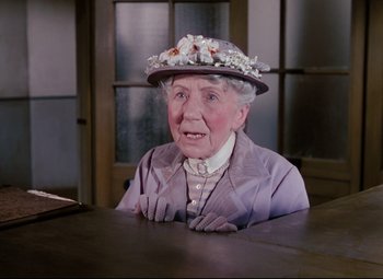 Movie still from “The Ladykillers” (1955), directed by Alexander Mackendrick – An older woman wearing a hat sitting at a table; Close Up shot, High angle