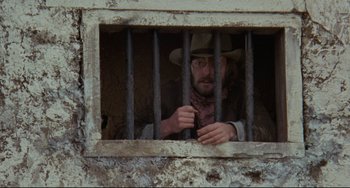 Movie still from “The Last Movie” (1971), directed by Dennis Hopper – A man in a cowboy hat looking out of a jail cell; Medium shot, Low angle