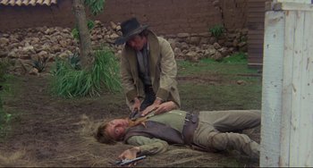 Movie still from “The Last Movie” (1971), directed by Dennis Hopper – A man in a cowboy hat is cutting a man's chest; Medium shot, Over the shoulder angle