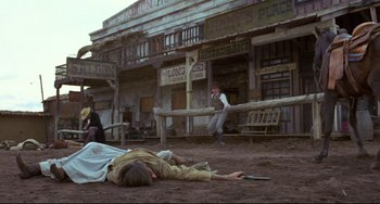 Movie still from “The Last Movie” (1971), directed by Dennis Hopper – A man is laying on the ground in the middle of a town; Wide shot, Low angle