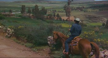 Movie still from “The Last Movie” (1971), directed by Dennis Hopper – A man riding a horse down a dirt road; Wide shot, High angle