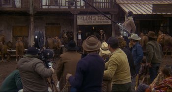 Movie still from “The Last Movie” (1971), directed by Dennis Hopper – A group of people standing in front of a building; Wide shot, Over the shoulder angle