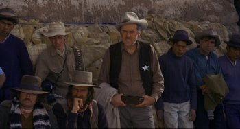 Movie still from “The Last Movie” (1971), directed by Dennis Hopper – A group of men standing next to each other on a rock wall; Medium shot, Over the shoulder angle