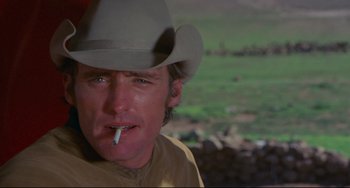 Movie still from “The Last Movie” (1971), directed by Dennis Hopper – A man in a cowboy hat is smoking a cigarette; Close Up shot, Low angle