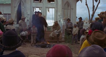Movie still from “The Last Movie” (1971), directed by Dennis Hopper – A group of people gathered around a fire pit; Wide shot, Over the shoulder angle