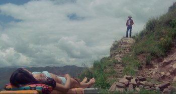 Movie still from “The Last Movie” (1971), directed by Dennis Hopper – A woman laying on the ground in front of a man; Extreme Wide shot, Low angle
