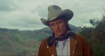 Movie still from “The Last Movie” (1971), directed by Dennis Hopper – A man wearing a cowboy hat and a brown jacket; Close Up shot, Low angle